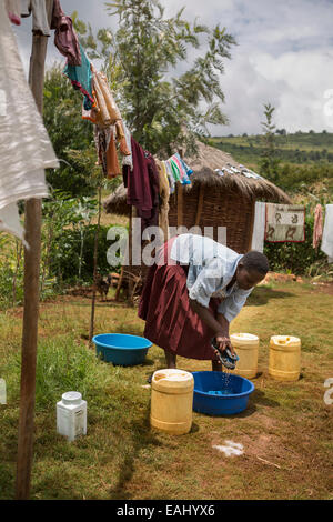 Une femme lave et sèche linge dans sa cour à Bukwo, District de l'Ouganda. Banque D'Images