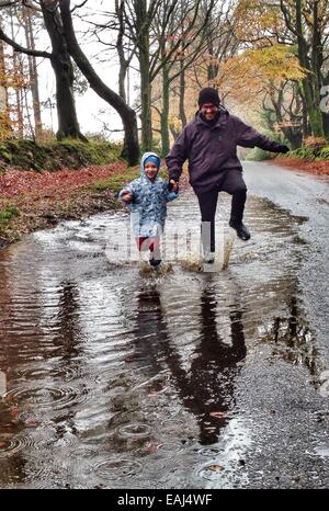 Haldon Forest, Devon, UK. Le 16 novembre, 2014. Météo britannique. Avoir un temps d'éclaboussures au maximum de temps humide. Jack Porter (6) et ses parents ayant un temps d'éclaboussures dans Haldon Forest après de fortes pluies. Nidpor Crédit/Alamy Live News Banque D'Images