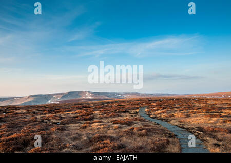 Sentier asphalté le long du Pennine Way avec la fin de l'hiver la neige. Vue vers Bleaklow sous un grand ciel bleu. Banque D'Images