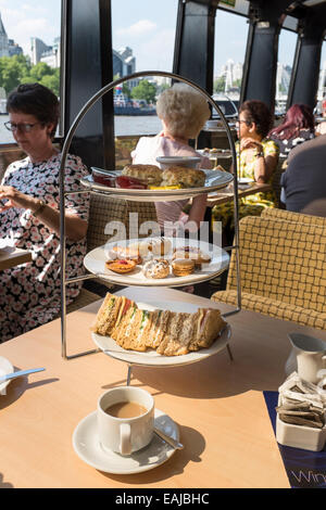 Sandwiches, gâteaux et des scones avec une tasse de thé sont tous partie d'un après-midi, excursion en bateau sur la Tamise. Banque D'Images