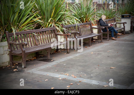 Femme adulte solitaire assis tout seul avec la tête dans les mains assis sur un banc par elle-même, Southport, Merseyside, Royaume-Uni Banque D'Images