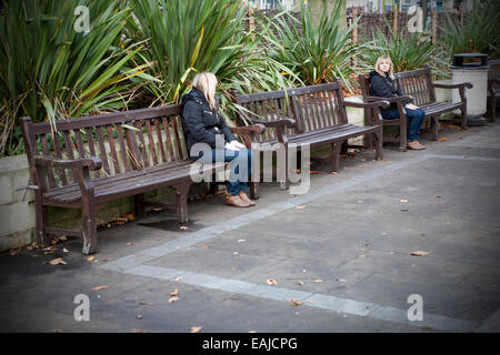 Femme adulte solitaire assis tout seul avec la tête dans les mains assis sur un banc par elle-même, Southport, Merseyside, Royaume-Uni Banque D'Images