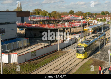 Tramway Metrolink à l'arrêt, la ligne Aéroport Wythenshawe, Manchester, Angleterre, RU avec nouvelle correspondance en construction. Banque D'Images