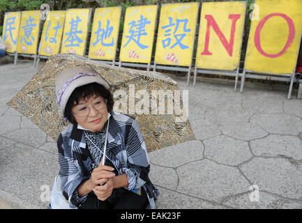 (141117) -- NAGO, le 17 novembre 2014 (Xinhua) -- une femme assise en face d'une bannière qui signifie : "l'opinion publique dit non à la construction d'une nouvelle base américaine' dans Henoko, dans la ville de Nago, Okinawa prefecture, Japon, le 17 novembre 2014. Ancien maire de Naha Takeshi Onaga, un 64-year-old adversaire de la base aérienne américaine de Futenma relocation plan, le dimanche a remporté l'élection au poste de gouverneur de la préfecture la plus au sud du Japon, d'Okinawa. (Xinhua/Stringer) Banque D'Images