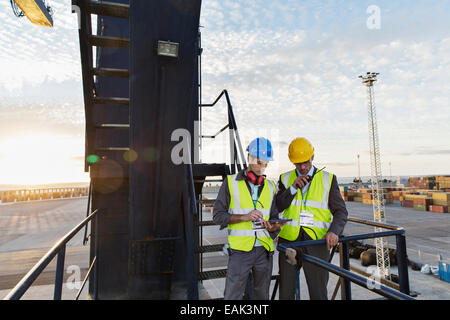 Les travailleurs utilisant walkie-talkie sur grue de chargement Banque D'Images