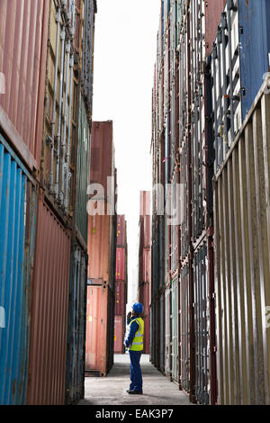 Worker standing entre les conteneurs de fret Banque D'Images