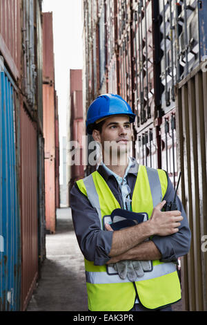 Worker standing entre les conteneurs de fret Banque D'Images