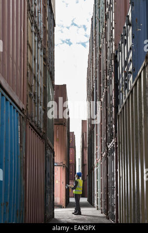 Worker standing entre les conteneurs de fret Banque D'Images