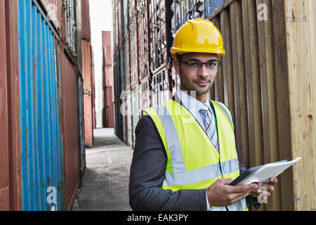 Businessman holding digital tablet entre les conteneurs de fret Banque D'Images