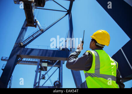 Low angle view of businessman using walkie-talkie sous grue de chargement Banque D'Images