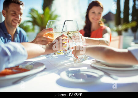 Friends raising toast at table outdoors Banque D'Images