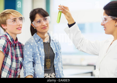 Les élèves avec leur enseignant travaillant en laboratoire de chimie, professeur holding test tube avec un liquide vert Banque D'Images