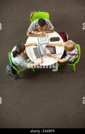 Vue aérienne d'élèves à faire leurs devoirs ensemble, à l'aide d'ordinateur portable et tablette numérique