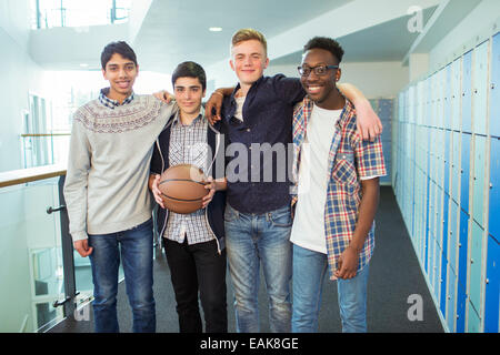Portrait de groupe des étudiants masculins holding basketball dans couloir d'école Banque D'Images