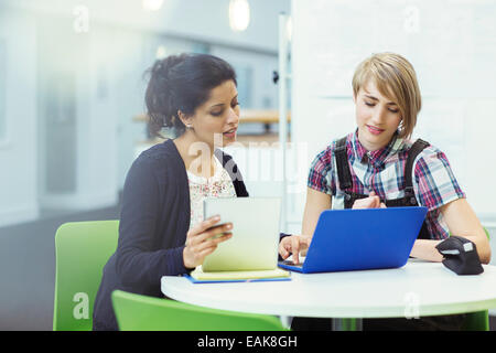 Le professeur et l'étudiant assis ensemble avec ordinateur portable et tablette numérique Banque D'Images