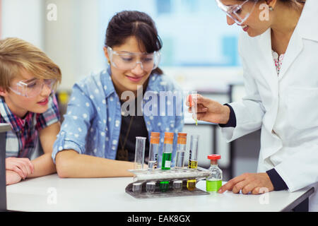 Le professeur et les élèves pendant la leçon de chimie, le port des lunettes de protection et à la recherche à tubes à essai Banque D'Images