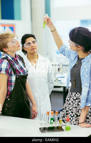 Le professeur et les élèves pendant la leçon de chimie, le port des lunettes de protection et à la recherche de tube à essai avec un liquide vert Banque D'Images