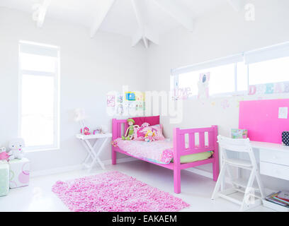 Girl's chambre avec lit rose, tapis et jouets Banque D'Images