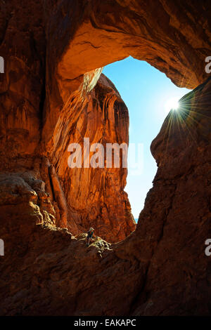 Hiker relaxing sous la Double Arch, voûtes en pierre de grès rouge formé par l'érosion, Arches-Nationalpark, près de Moab, Utah Banque D'Images