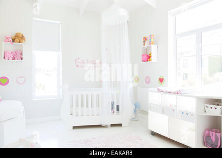 Lit bébé blanc avec tulle auvent dans la chambre de bébé de couleur pastel Banque D'Images