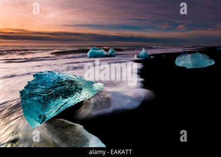 Des morceaux de glace sur la plage de lave noire au lever du soleil, Jökularsalon, Vik, Islande Banque D'Images