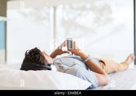 L'homme à l'écoute de la musique tout en lying on bed Banque D'Images