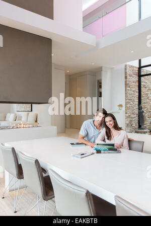 Portrait of couple sitting in salle à manger avec des livres, des journaux et de tablette numérique sur table Banque D'Images