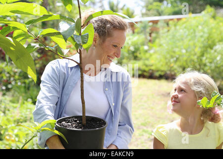 Femme et fille avec d arbre dans le jardin ensoleillé Banque D'Images