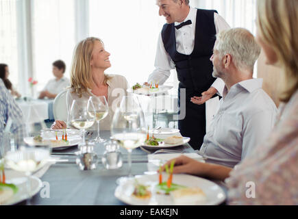 Waiter serving dish fantaisie à woman sitting at table Banque D'Images