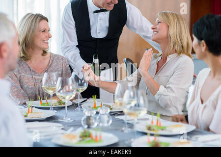 Waiter offering vin à table au restaurant-clientes, femme refusant Banque D'Images