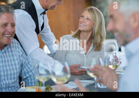 Waiter serving food to woman in restaurant Banque D'Images