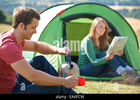 Couple boisson chaude tout en camping à la campagne Banque D'Images