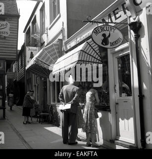 Années 1950, historique, les gens regardant dans les fenêtres des magasins d'antiquités dans une jolie ruelle dans la vieille partie de Hastings sur la côte East Sussex, en Angleterre. La vieille ville de Hastings a de nombreux passages pittoresques et de nombreux bâtiments historiques. Banque D'Images