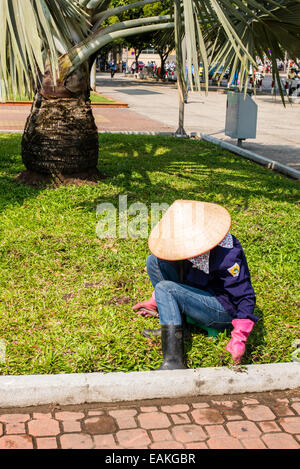 Jardinier femme portant Chapeau conique traditionnel tout en travaillant dans un parc à Ho Chi Minh Ville, Vietnam Banque D'Images