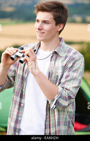 Jeune homme avec des jumelles On Camping Trip Banque D'Images