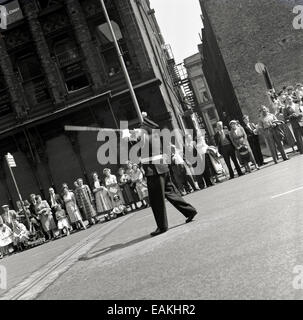 Années 1950, historique, les gens regardent au bord de la route dans le centre-ville de Manchester alors qu'un groupe marche dans le défilé traditionnel Whitsun pour célébrer l'anniversaire de l'église chrétienne. Ces processions remontent à 1784 et à la naissance du mouvement de l'école du dimanche. Banque D'Images