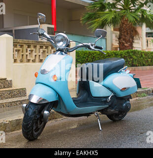 Scooter bleu garée dans la rue. Banque D'Images