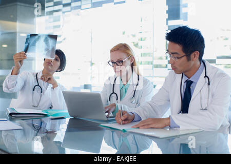 Les médecins à l'aide d'ordinateur portable et regarder des rayons x du patient Banque D'Images