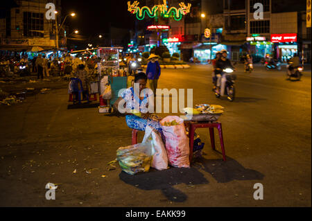 Vendeur femme maïs grillé de vente au marché de nuit dans les rues de Tra Vinh, Vietnam. Banque D'Images