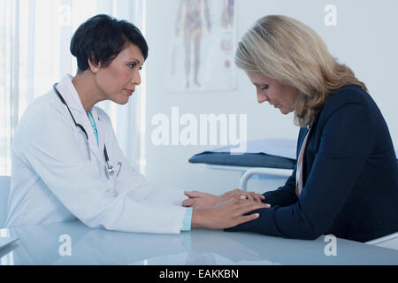 Femme médecin femme triste consolation at desk in office Banque D'Images