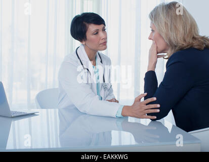 Femme médecin femme triste consolation at desk in office Banque D'Images