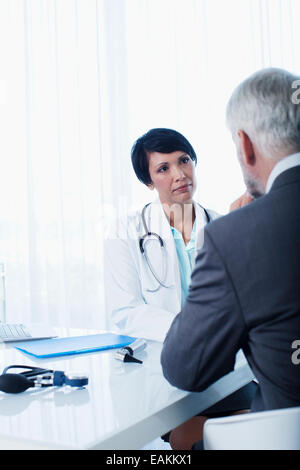 Femme médecin et man sitting at desk in office Banque D'Images