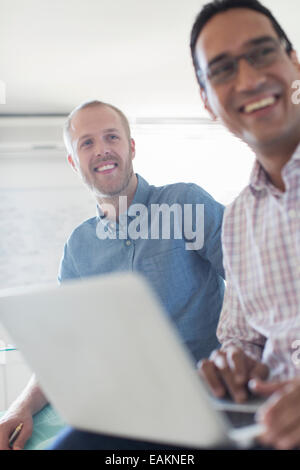 Deux smiling businessmen using laptop in office Banque D'Images