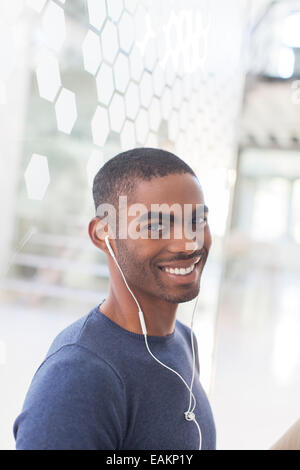Portrait of smiling young man with earphones in office Banque D'Images