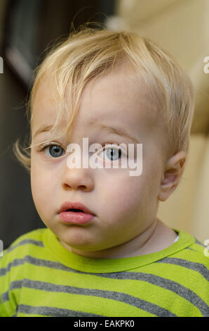 Une pensive-à la blonde et blue-eyed baby boy (ca. 18 mois). Banque D'Images