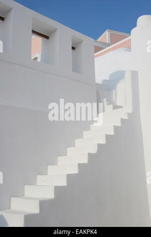Escalier en pierre blanche entre deux murs blancs avec Abri international ci-dessus, Oia, Santorin, Grèce. Banque D'Images