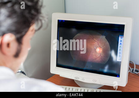 Un jeune ophtalmologiste à à un scan de la rétine dans l'écran d'un ordinateur Banque D'Images