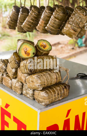 Traiter les Vietnamiens enveloppées dans des feuilles de bananier pour la vente par le côté de la route à Tra Vinh, Delta du Mekong, Vietnam. Banque D'Images