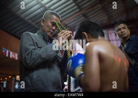 Chiang Mai, Thaïlande. 24 Jan, 2014. Un Mong Kon (Muay Thai cérémonie chapeau) est placée sur la tête d'PETCHFOGUS SITTHAHARNAEK, 9, aka point avant son combat au stade de Muay Thai Thapae. Il a commencé la lutte contre les anciens adversaires plus lourds, de continuer à améliorer ses compétences. Combattants sont généralement versées 1 000 bahts (30 dollars) par lutte. © Taylor Weidman/ZUMA/ZUMAPRESS.com/Alamy fil Live News Banque D'Images