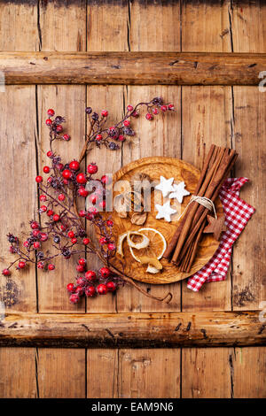 Les cookies de Noël, noix, écorce d'orange séchée, des bâtons de cannelle et de la direction générale aux fruits rouges sur fond de texture en bois Banque D'Images